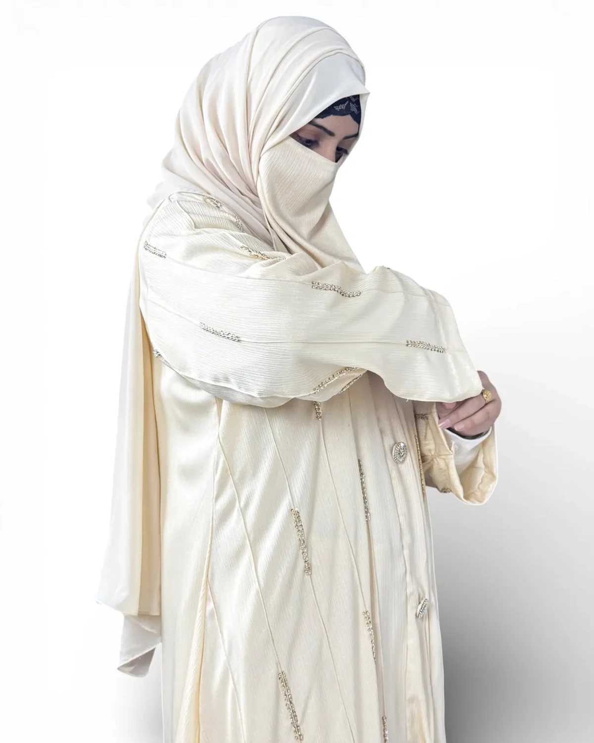Royal Ivory cream abaya angled view showing vertical pintuck stripes and decorative buttons