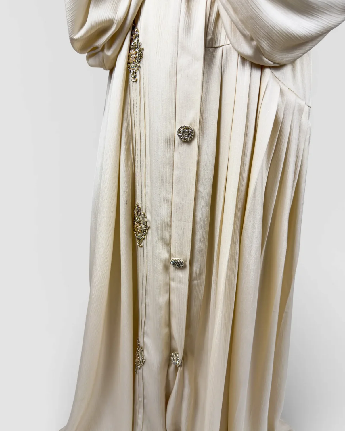 The Vanilla cream abaya close-up of jeweled ornament and round decorative button detail