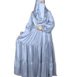 Blue Tiers dusty blue abaya front three-quarter view with softly tiered high-sheen satin skirt