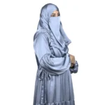 Blue Tiers dusty blue abaya front three-quarter view with softly tiered high-sheen satin skirt