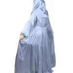 Blue Tiers dusty blue abaya front three-quarter view with softly tiered high-sheen satin skirt